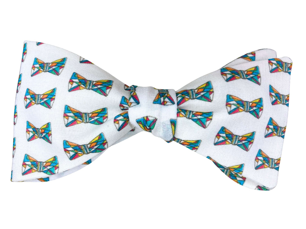 A white self-tie bow tie featuring a repeating pattern of colorful geometric bow ties in shades of blue, yellow, red, and green.