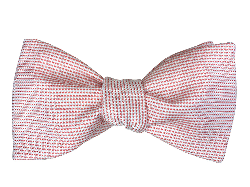 Bow tie featuring a fine micro-pattern of small coral dits on a white background.
