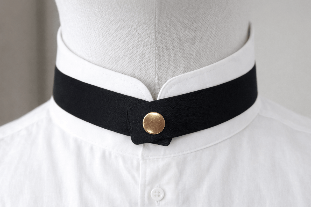 modern continental crossover black silk tie with gold pop stud on a mandarin shirt collar 