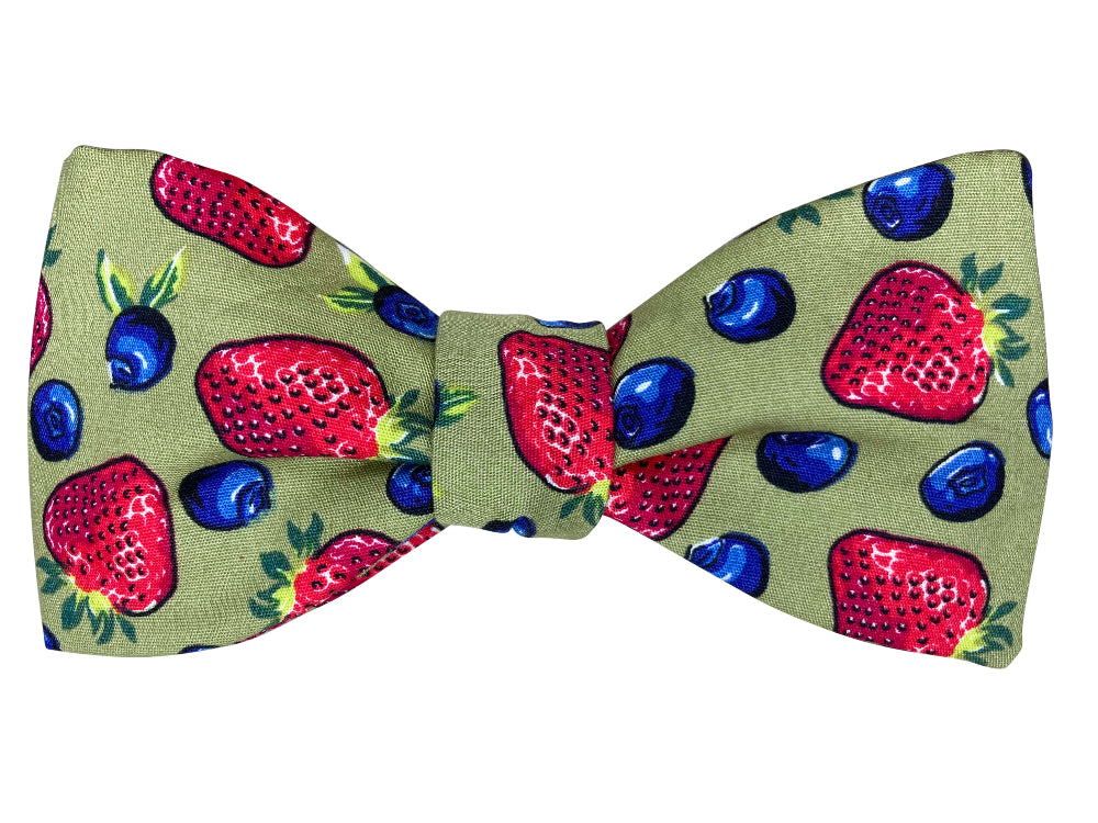 Bow tie with strawberry and blueberry pattern on a green background